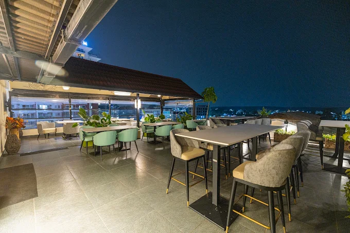 High tables on the open-air rooftop terrace at Stories Brew Garden, with the skyline behind at dusk